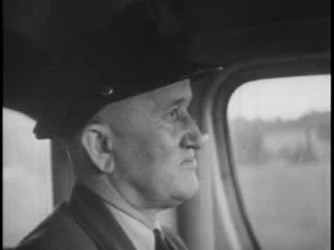 Bus driver looking out window while driving, uniform, hat.