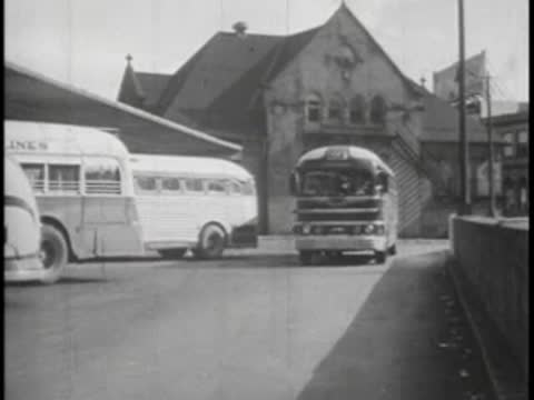 Buses parked at bus station terminal building, 1940s city.
