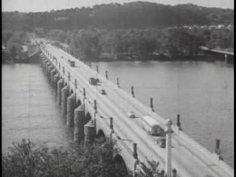 High-angle view of a multi-lane stone bridge over a river with vintage traffic.