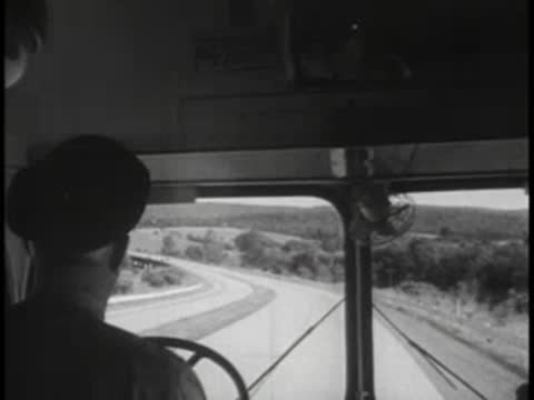 Driver's viewpoint looking through the windshield at a winding rural highway ahead.