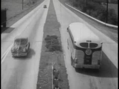 High-angle tracking shot of a bus and car driving along a divided highway.
