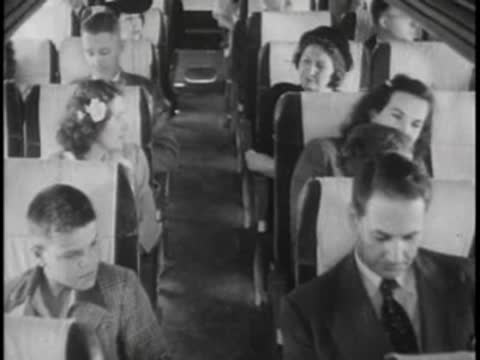 Passengers sitting inside a crowded bus, including a boy and a man reading.