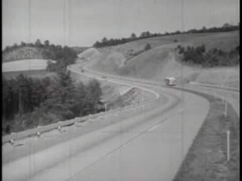 Tracking shot of a winding mountain road with a bus traveling ahead.