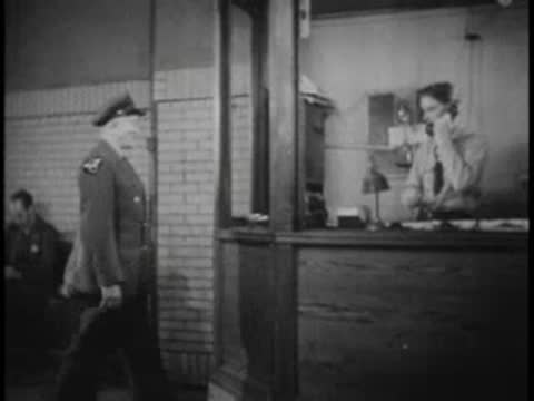 Bus terminal dispatcher walks across the room toward a window counter