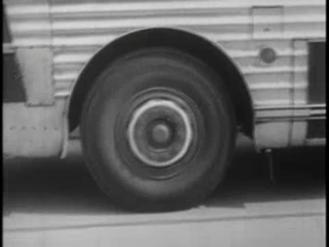 Tracking shot shifting from the side of a moving bus to passengers inside.