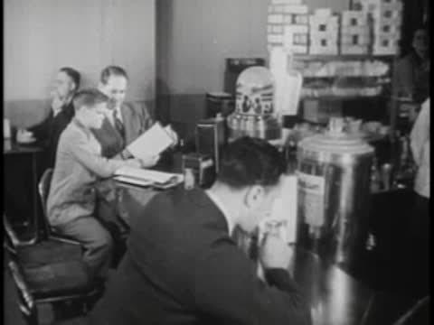 People sitting at a service counter inside a station with a water dispenser.