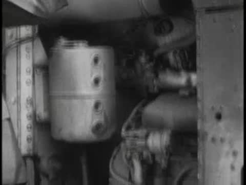 Open engine compartment of a vehicle showing mechanical parts and fluid reservoir.