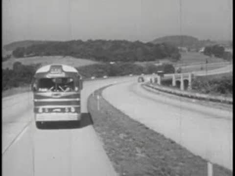 Bus driving along scenic highway, vintage vehicle, mid-20th century.