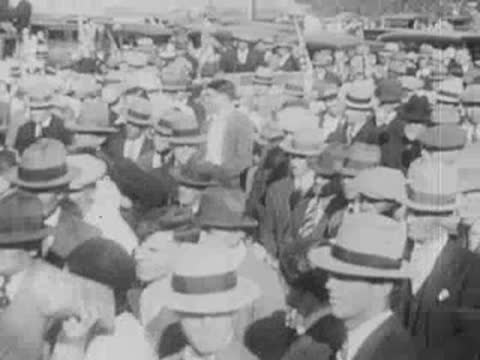 Dense crowd of people wearing hats listening intently outdoors.