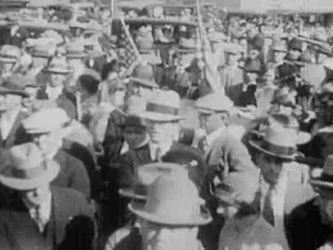 Large crowd of people outdoors, with some holding American flags.