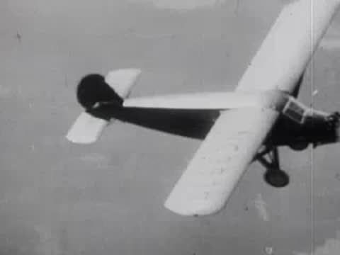 Single-engine airplane flies through the air over a landscape.