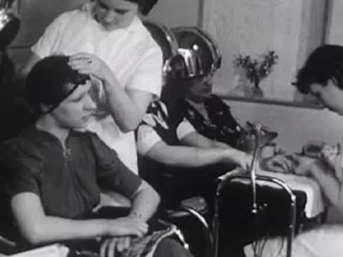 Stylist working on a customer's hair while others sit nearby.