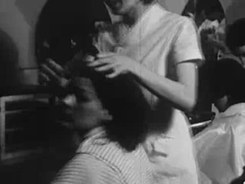 Stylist brushing and styling a customer's dark hair.