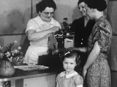 Stylist working at the front counter with a customer and young girl watching.