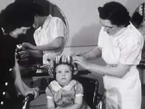 Stylist working on a young girl's hair with curlers inside the salon.