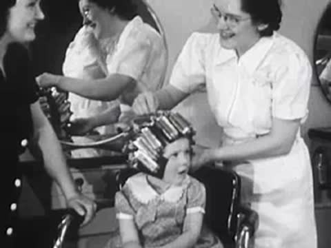 Stylist continuing to adjust curlers on a young girl's hair.