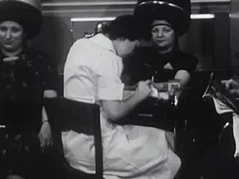 Stylist working at a station while a customer reads a book.