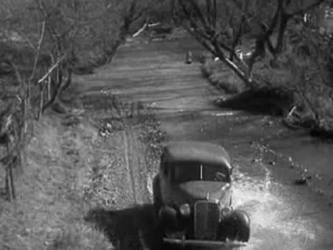 Car splashing through water while driving across a shallow riverbed