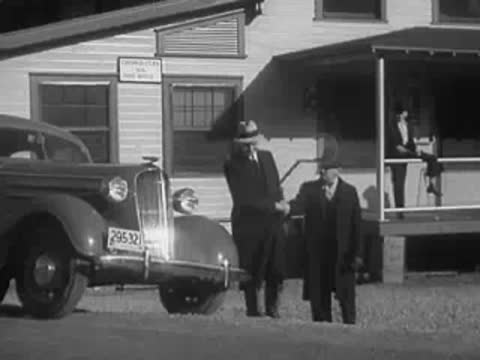 Two men in hats walking away from a parked sedan