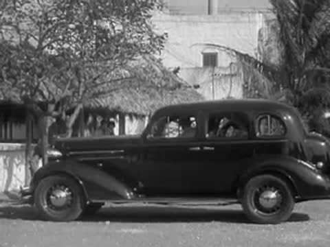 Stationary side view of a 1930s sedan parked in a sunny outdoor area
