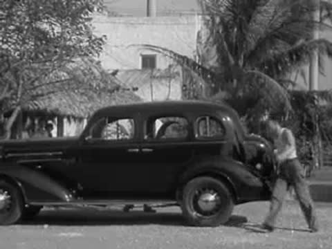 Man walking up to the rear door of a parked sedan