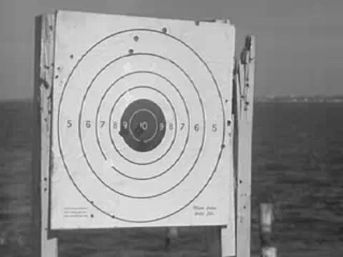 A car drives through dirt and sand toward shooting targets.