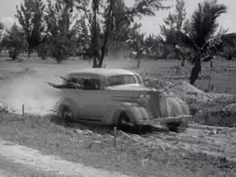 A car maneuvers through sandy, uneven terrain with dust kicking up.