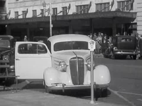 A white car is parked on a city street next to a parking meter.