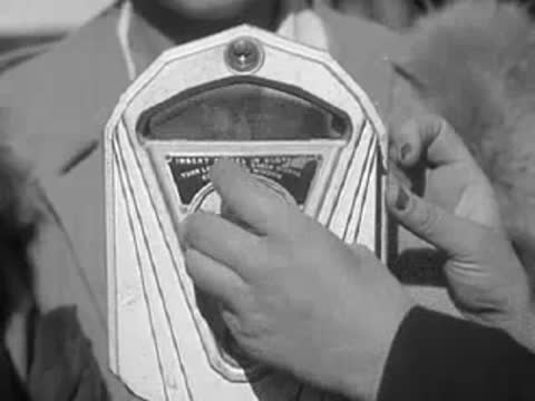 Close-up of a hand operating a coin parking meter.