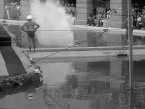 divers leap from high platforms into a large outdoor pool