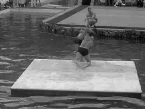 men wrestle on a floating mat in the middle of a pool