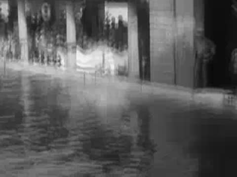 a man dives into a swimming pool from a suspended pole