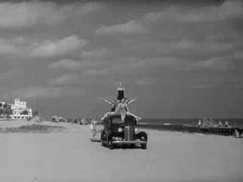 Woman running on beach pulling a rope as a car approaches