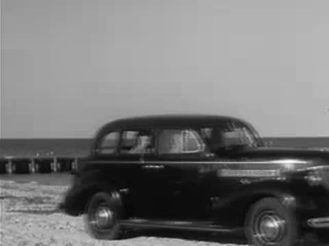 Parked car on beach and woman standing in swimsuit