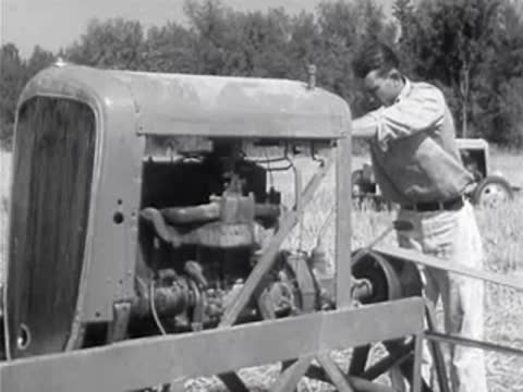 Worker tending engine of rice harvester in field