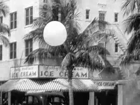 Weather balloon floating in the sky above Miami street with Dolly Dixon ice cream shop