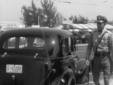 Police officer standing by a vintage police car with Miami license plate