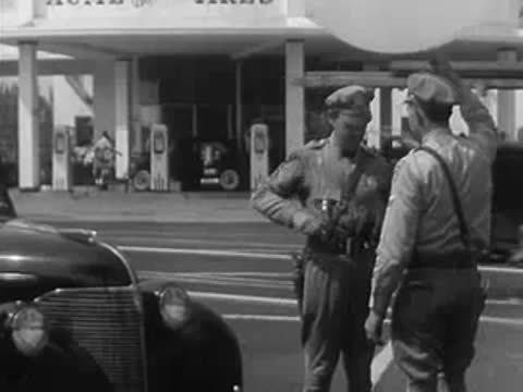 Two police officers meeting by a parked car, one holding a weather balloon string