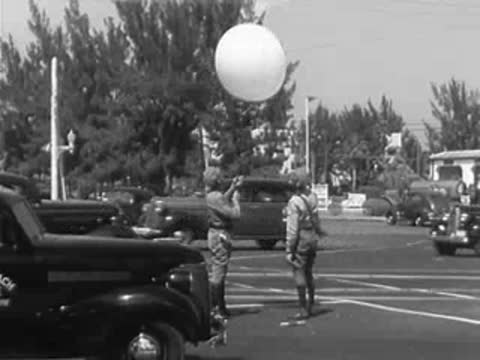 Two police officers releasing a weather balloon at a service station intersection