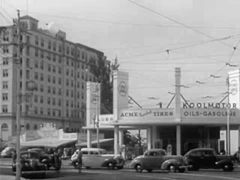 Weather balloon ascending over a city street with Acme Tires and Koolmotor gasoline station