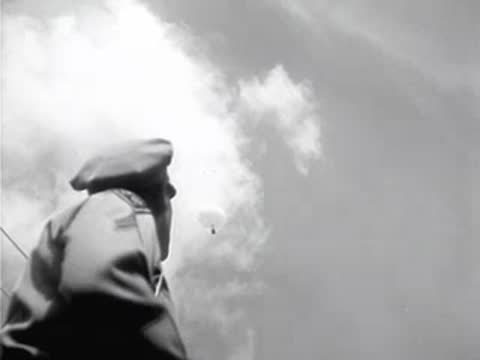 Police officer in uniform looking up at a weather balloon in the cloudy sky
