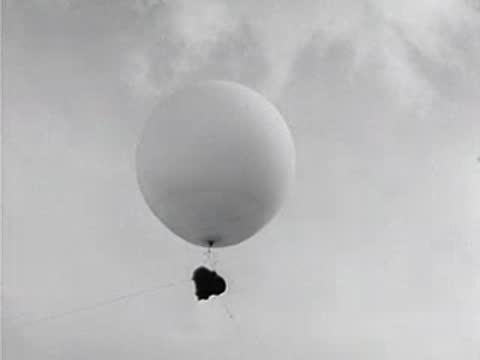 Weather balloon with scientific instrument attached floating in the sky