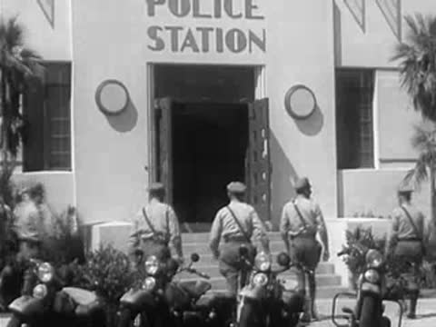 Police officers in uniform walking into a police station building
