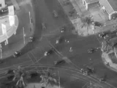Aerial view of a busy city intersection with cars and tropical foliage