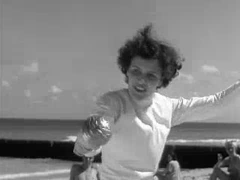 Fencer smiling and holding fencing foil on beach