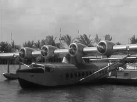 Pan American seaplane docked on water, engines running.