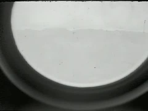 A view looking out a circular airplane porthole at a landscape.