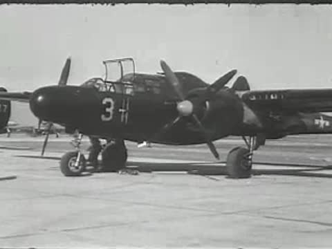 A parked vintage military-style twin-engine airplane on an airfield.