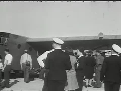 People boarding a military transport aircraft outdoors.