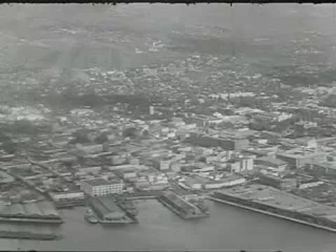 An aerial view showing a coastal city with a harbor and buildings.